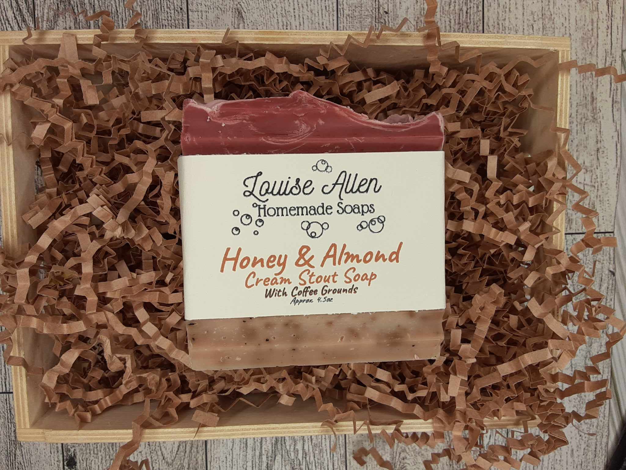 Bar of soap with a label on crinkled brown paper in a wooden box.