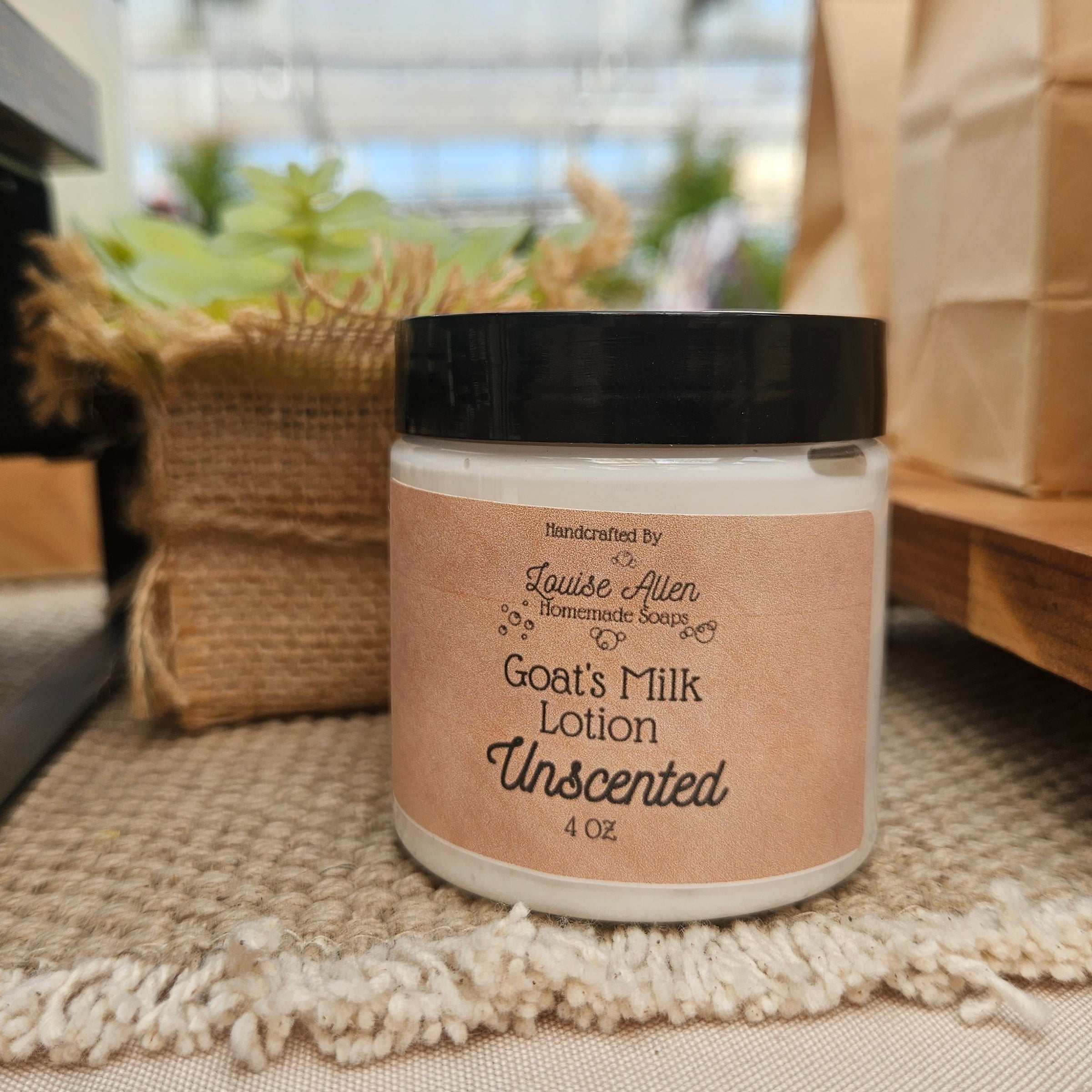Jar of goats' milk lotion with a brown label on a textured surface.