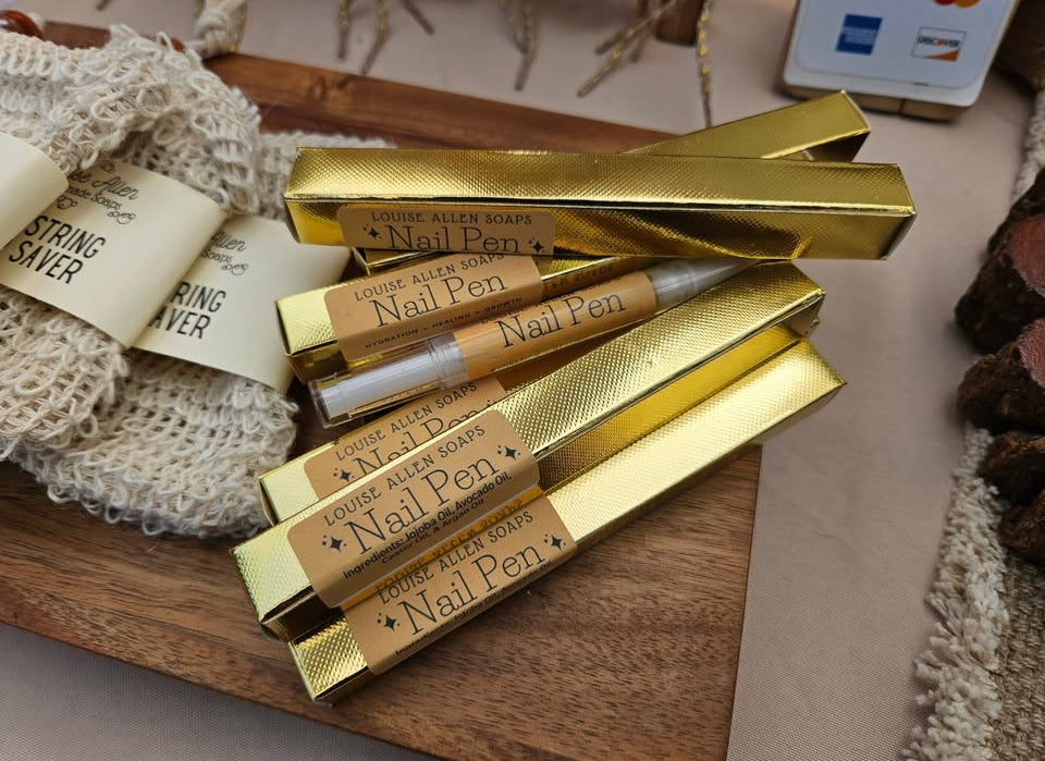 Gold nail art pens with branded labels on a wooden tray.