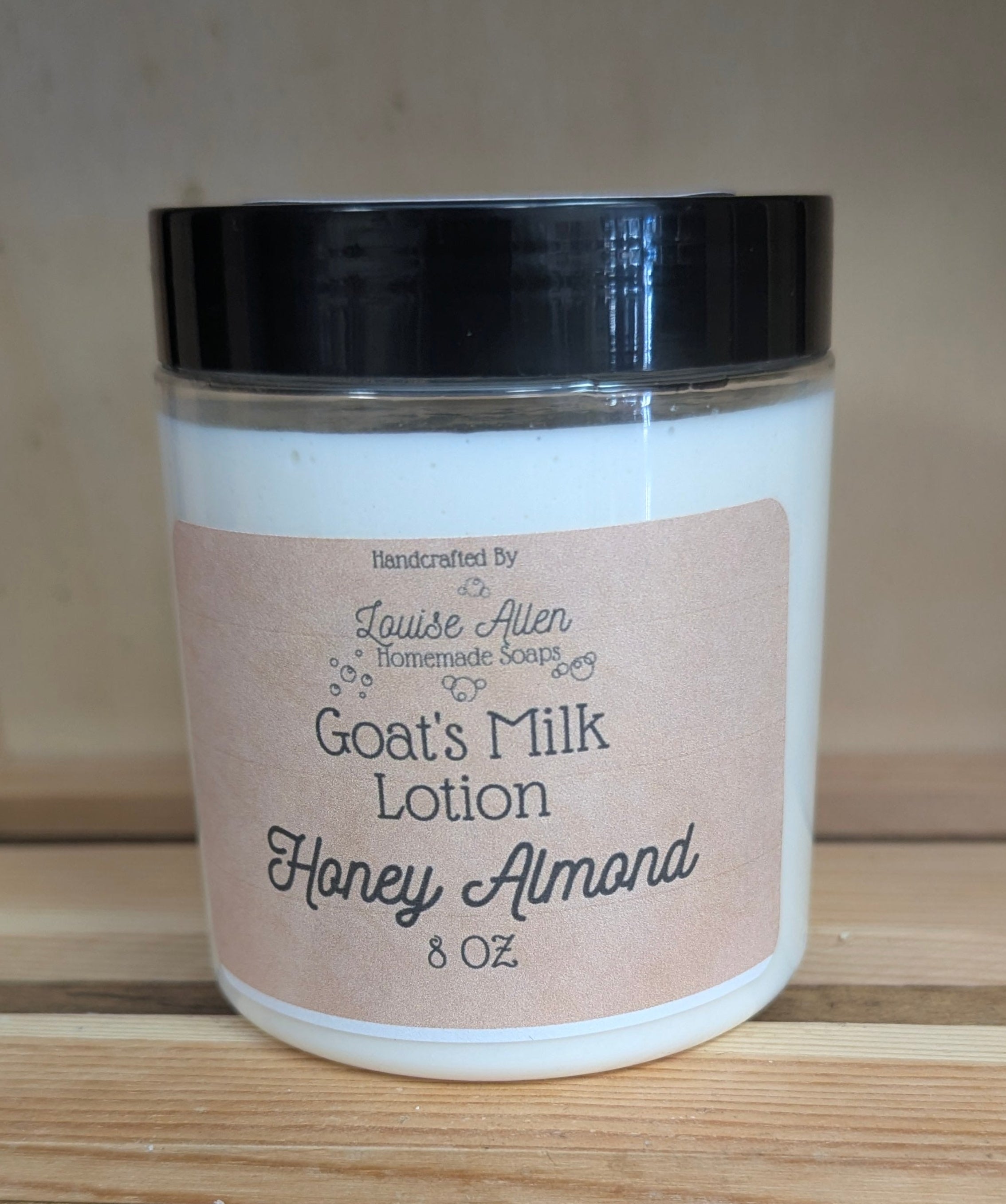 Jar of goat's milk lotion labeled 'Honey Almond' on a wooden surface