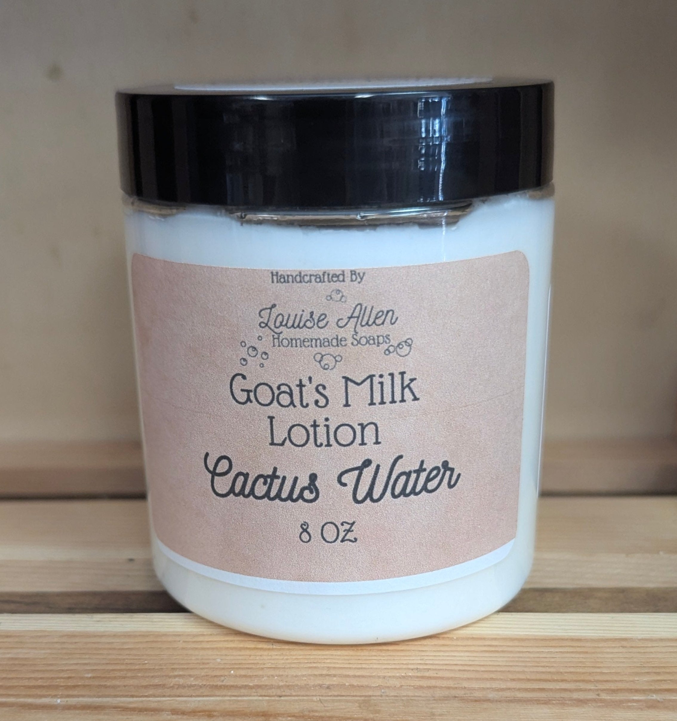 Jar of goats' milk lotion with a black lid on a wooden surface