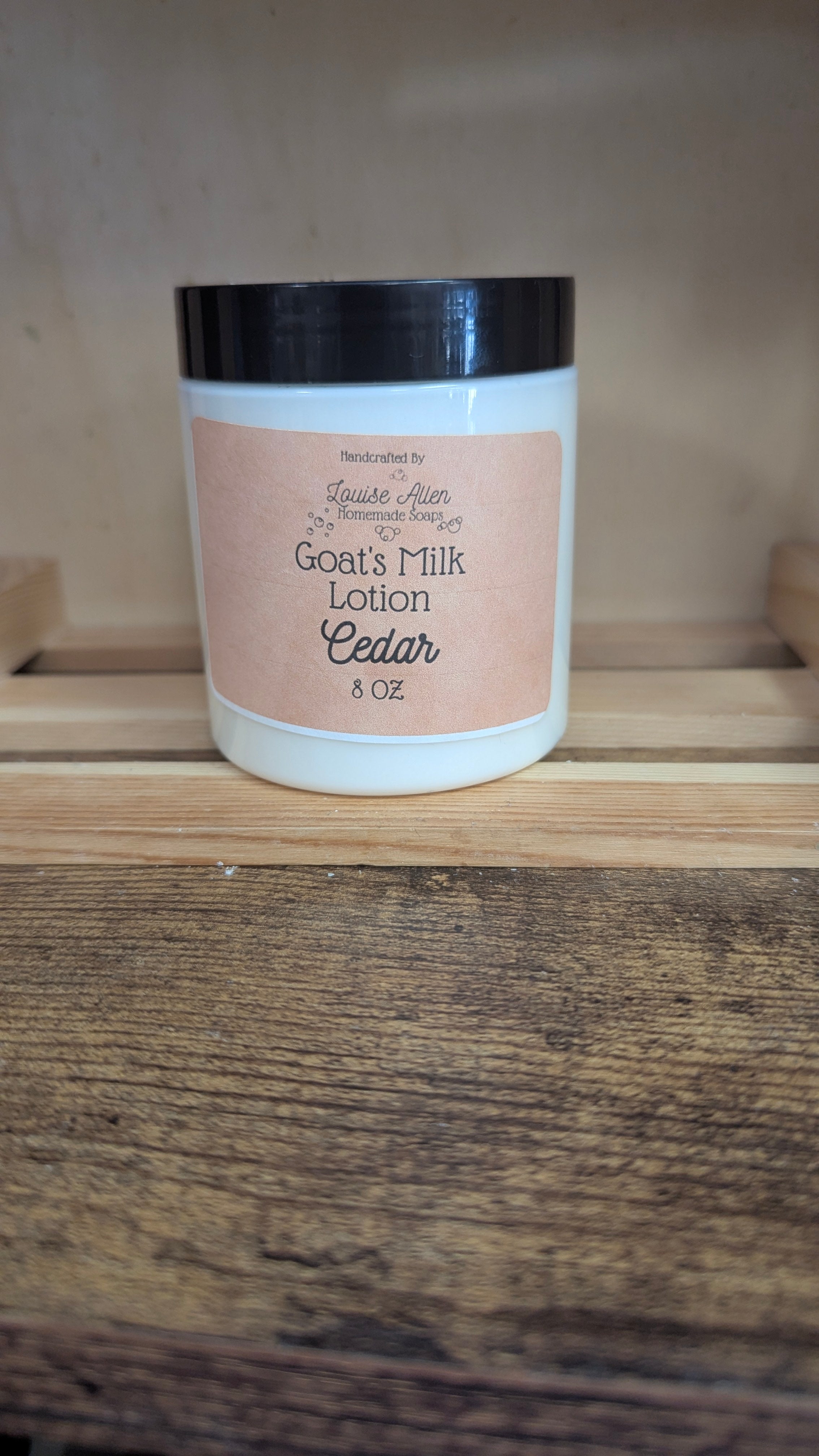 Jar of goat's milk lotion labeled 'Cedar' on a wooden surface