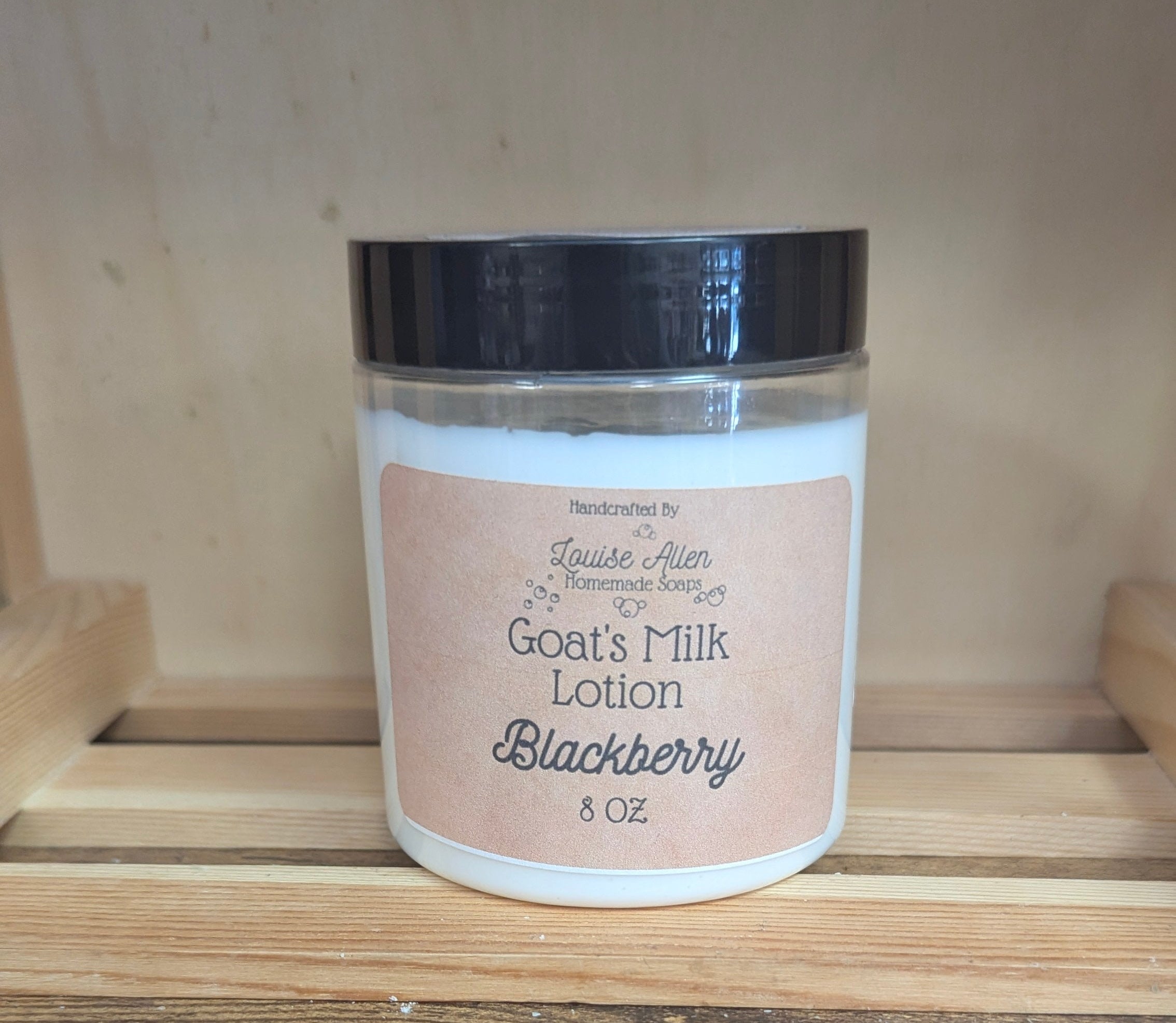Jar of goat's milk lotion labeled 'Blackberry' on a wooden surface