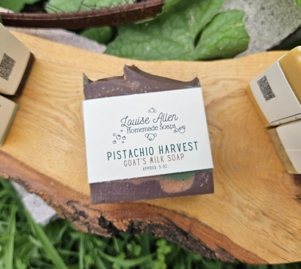 Goat's milk soap bar with a label on a wooden surface surrounded by greenery