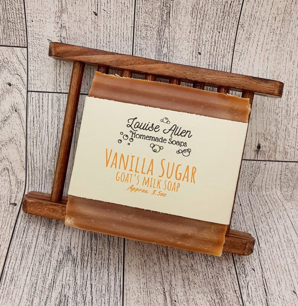 Vanilla sugar goat's milk soap on a wooden stand with a label on a wooden surface